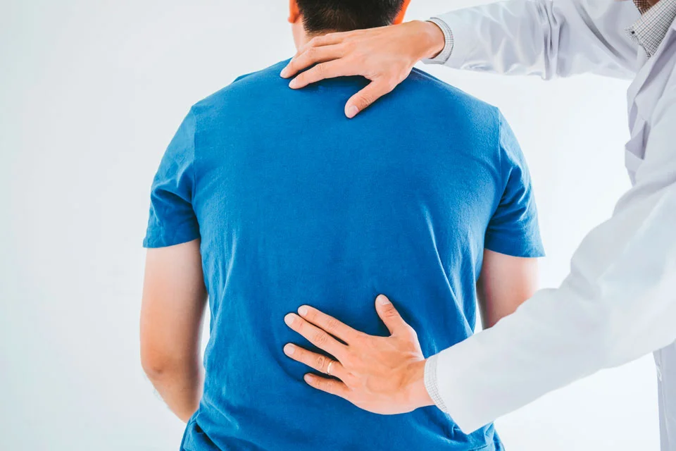 A chiropractor places their hands on a patient's back to assess spinal alignment and provide treatment for back pain or discomfort - Chiropractor Louisville KY