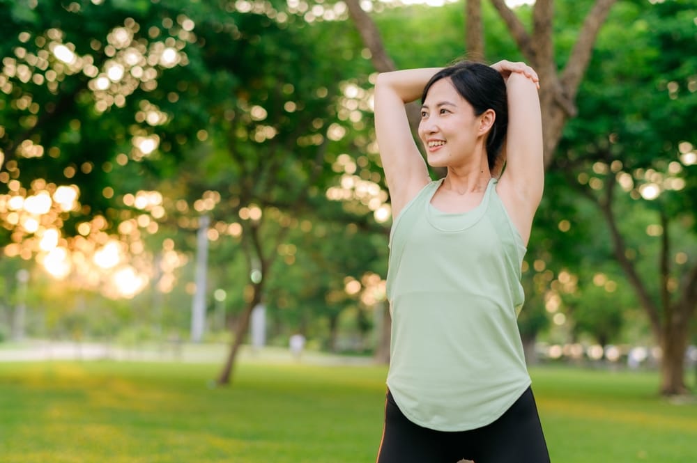 A woman stretches outdoors at sunset, supporting flexibility, mobility, and healthy living - Chiropractor in Fern Creek.