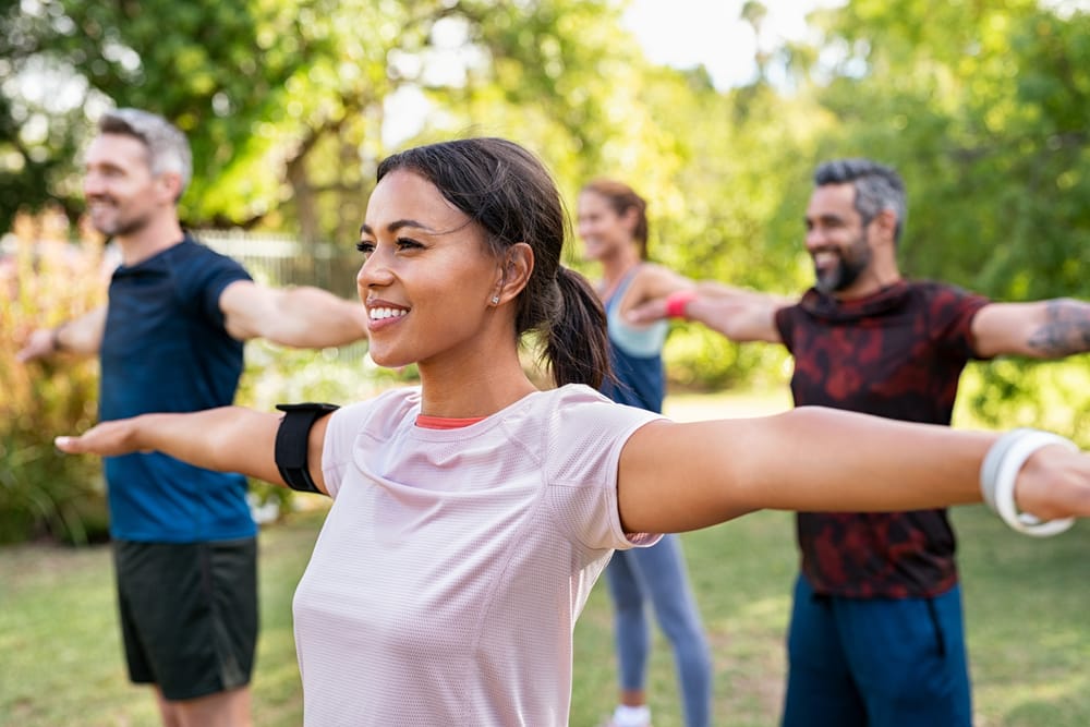 A group of people enjoy outdoor fitness exercises to boost health, mobility, and overall wellness - Chiropractor in Fern Creek.