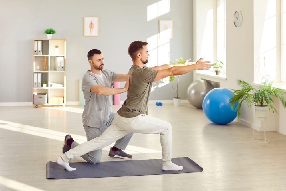 Guided Stretching Therapy - Chiropractor in Hillview, KY A therapist assists a man with guided lunge stretching to improve mobility, balance, and recovery - Chiropractor in Hillview, KY.