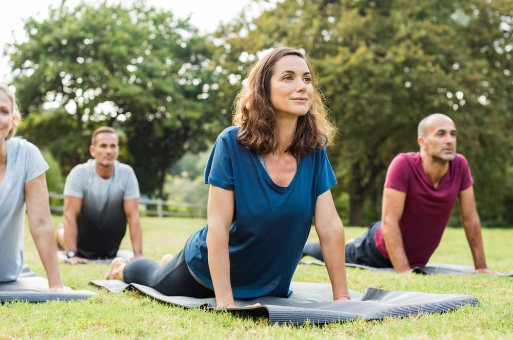 A group practices yoga stretches outdoors, improving posture, strength, and relaxation - Chiropractor in Jeffersontown, KY.