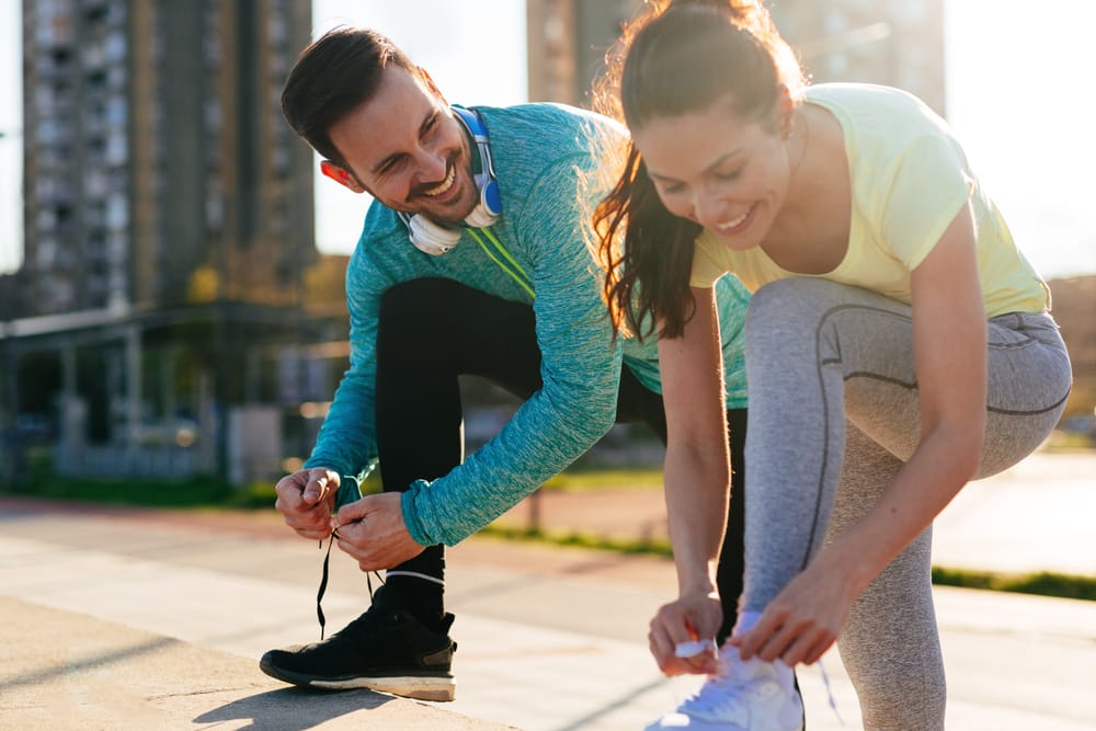 A smiling couple ties their shoes before exercising, promoting energy, wellness, and an active lifestyle - Chiropractor in Fern Creek.