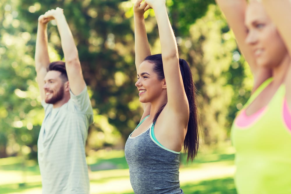 A group participates in outdoor stretching exercises, boosting energy, flexibility, and overall wellness - Okolona Chiropractor.
