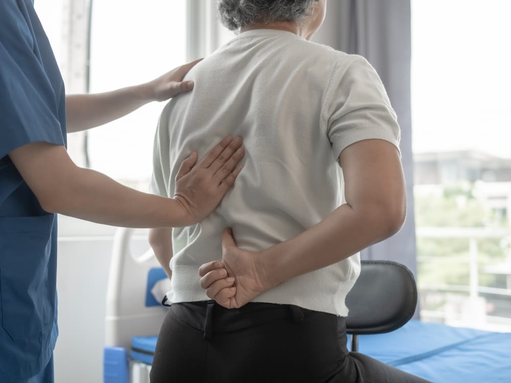 Back Pain Care and Support - Rehabilitation A healthcare provider supports an elderly patient experiencing back pain, focusing on recovery, mobility, and improved quality of life - Rehabilitation.