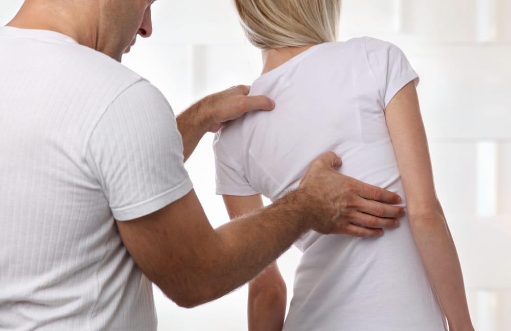 Professional Back Therapy and Support - Electro-Muscle Stimulation A therapist examines a patient’s back, providing relief and recovery assistance enhanced by Electro-Muscle Stimulation.