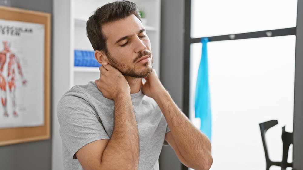 Neck Pain Relief Consultation – Louisville Auto Accident Chiropractor A man gently holds his neck in discomfort while consulting a chiropractor for whiplash and neck strain after a car accident – Louisville Auto Accident Chiropractor.